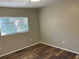 Spare room with dark wood-style flooring and baseboards