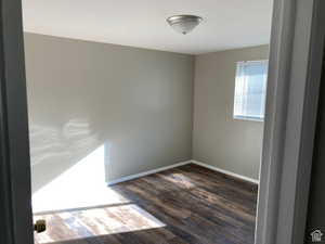 Unfurnished room with dark wood-style flooring and baseboards