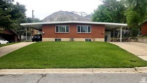 View of front of property with concrete driveway, brick siding, a carport, and a mountain view