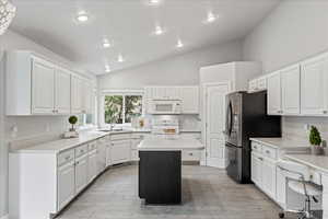 Kitchen featuring light countertops, white cabinetry, a center island, white appliances, and recessed lighting