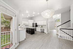 Kitchen featuring light countertops, white cabinets, light wood-style floors, pendant lighting, and a kitchen island