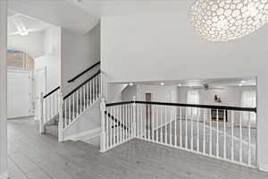 Staircase with a towering ceiling, wood finished floors, and a ceiling fan