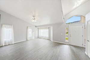 Entryway featuring healthy amount of natural light, light wood-style floors, a textured ceiling, high vaulted ceiling, and ceiling fan