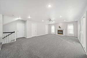 Unfurnished living room with carpet, a fireplace, and a ceiling fan
