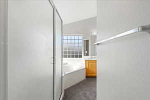 Bathroom featuring a textured wall, vanity, a stall shower, a bath, and dark colored carpet