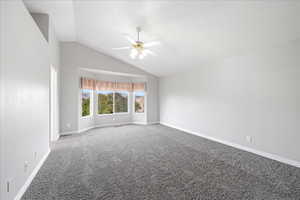 Carpeted empty room with vaulted ceiling and ceiling fan