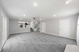 Unfurnished living room with light carpet, stairway, recessed lighting, and ceiling fan