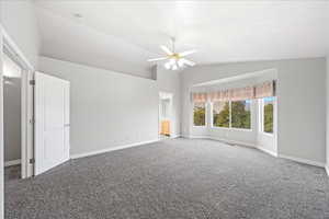 Carpeted empty room featuring lofted ceiling and ceiling fan
