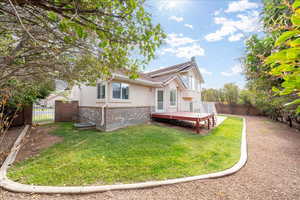 Rear view of house with a deck, a fenced backyard, brick siding, and stucco siding