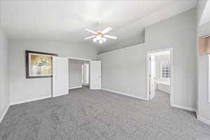 Unfurnished bedroom featuring lofted ceiling, light colored carpet, ceiling fan, and ensuite bathroom