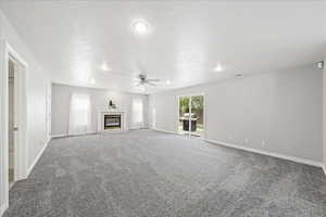 Unfurnished living room with a premium fireplace, light carpet, a textured ceiling, ceiling fan, and recessed lighting