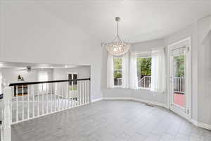 Spare room featuring a glass covered fireplace, vaulted ceiling, a ceiling fan, and light wood finished floors