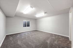 Carpeted spare room with a textured ceiling and baseboards