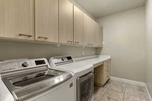 Laundry room featuring washer and dryer, light tile patterned flooring, and cabinet space