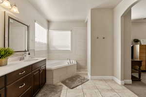 Full bath with a garden tub, vanity, a tile shower, and light tile patterned flooring