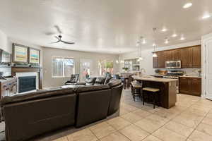 Living room featuring a chandelier, a glass covered fireplace, a ceiling fan, recessed lighting, and light tile patterned flooring