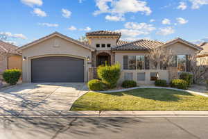 Mediterranean / spanish-style house featuring stucco siding, stone siding, an attached garage, driveway, and a front yard