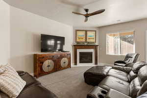 Carpeted living room featuring a fireplace and ceiling fan