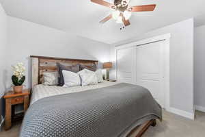 Bedroom with light carpet, a closet, and ceiling fan