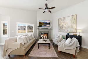Living room featuring a warm lit fireplace, hardwood / wood-style flooring, and a ceiling fan