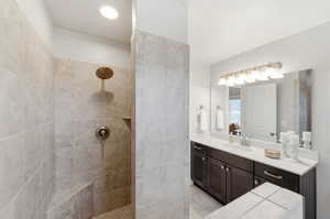 Full bath featuring tiled shower and vanity