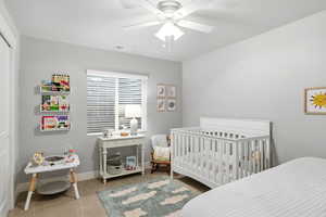 Bedroom featuring a nursery area, a ceiling fan, and a closet