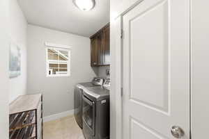 Laundry area featuring a textured ceiling, independent washer and dryer, cabinet space, and light tile patterned floors