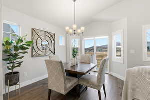 Dining space with dark wood-type flooring, lofted ceiling, and a chandelier