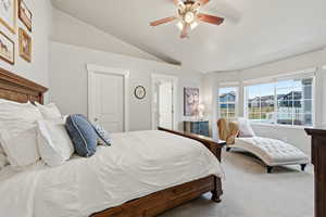 Carpeted bedroom featuring vaulted ceiling and ceiling fan
