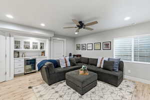 Living area with recessed lighting, wine cooler, light wood-style flooring, ceiling fan, and bar area