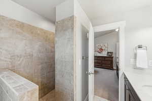 Bathroom with light colored carpet, walk in shower, vanity, and a textured ceiling