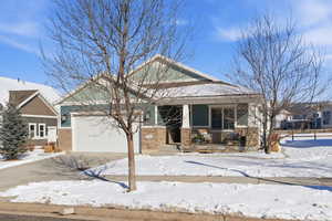 Craftsman-style home with a porch, brick siding, driveway, and a garage