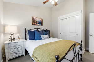 Carpeted bedroom featuring ceiling fan and a closet