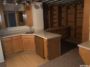 Kitchen featuring light countertops, a peninsula, brown cabinetry, and light wood-style floors
