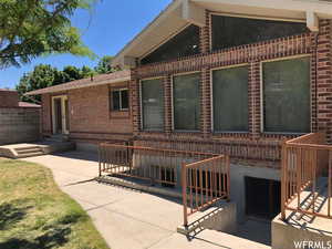 Doorway to property featuring brick siding and a patio area