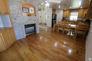 Dining space featuring light wood finished floors, a ceiling fan, a brick fireplace, and recessed lighting