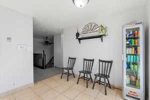 Sitting room with an upstairs landing, light carpet, a ceiling fan, and light tile patterned floors