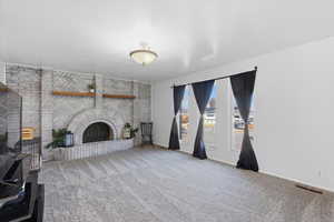 Unfurnished living room with carpet floors and a brick fireplace