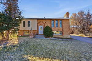 Raised ranch featuring brick siding and a chimney