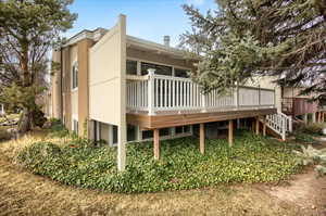 Rear view of house with a wooden deck, brick siding, and stairway