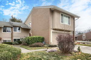 View of property exterior featuring stucco siding, an attached garage, brick siding, and driveway