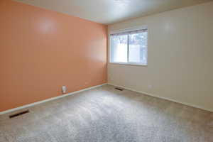 Spare room featuring carpet flooring and baseboards