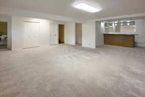 Unfurnished living room with light carpet, washer and dryer, and bar