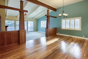 Unfurnished living room featuring beam ceiling, light wood-type flooring, a chandelier, and high vaulted ceiling