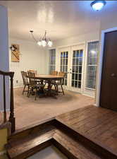 Dining room with french doors, a textured ceiling, carpet, and hanging lights