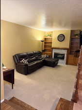 Living area featuring a premium fireplace, carpet, and a textured ceiling