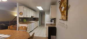 Kitchen featuring white cabinets, light tile patterned floors, dishwasher, and backsplash