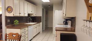 Kitchen with dark countertops, white cabinetry, and white appliances