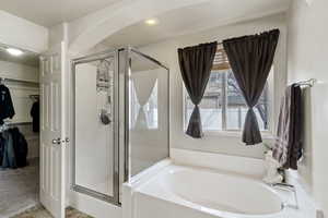 Full bathroom featuring a stall shower, a bath, a spacious closet, carpet floors, and recessed lighting
