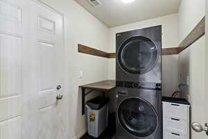Washroom with a textured ceiling and stacked washer / drying machine